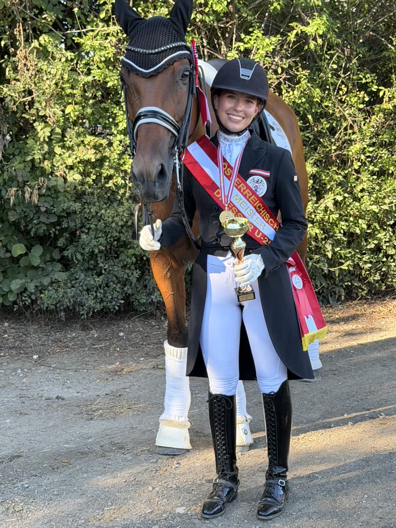 Dressurreiterin mit Schärpe, Pokal und Pferd bei der Siegerehrung